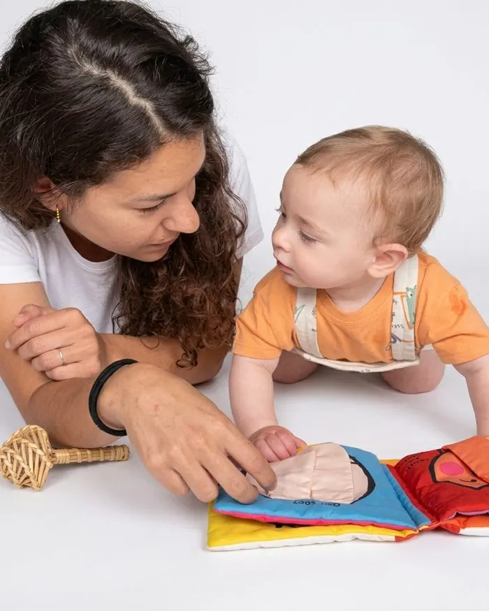 Terapeuta ocupacional jugando con un bebé con un libro sensorial de tela, atención temprana en casa